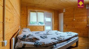 a bed in a wooden room with a window at На Ґанку in Verkhovyna