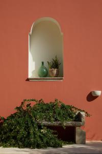 eine Wand mit einem Spiegel, einer Bank und Pflanzen in der Unterkunft Petra - Country House in Monteroni di Lecce