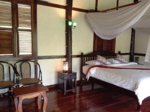 a bedroom with two beds and a canopy bed at Lao Spirit Resort in Ban Xianglôm