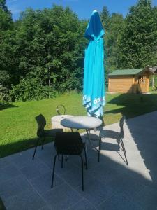 une table, des chaises et un parapluie bleu dans l'établissement Apartma Gače, à Semič