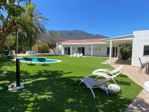 a yard with chairs and a pool and a house at Arafo Sunset Villa in Arafo