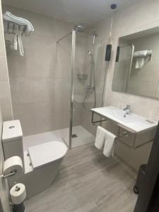a bathroom with a shower and a toilet and a sink at Hotel Lusitania, Centro Ciudad, Parking Privado in Mérida