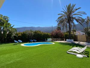 un patio con sillas y una piscina con césped en Arafo Sunset Villa, en Arafo