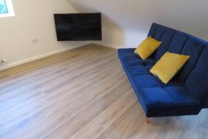 ein blaues Sofa mit zwei gelben Kissen im Wohnzimmer in der Unterkunft The Boat Shed, Westport in Westport