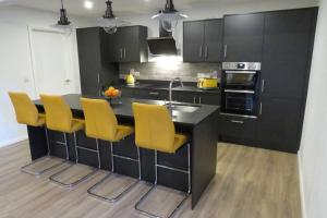 a kitchen with a black counter and yellow chairs at The Boat Shed, Westport in Westport
