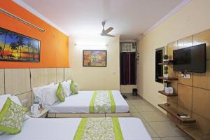 a hotel room with two beds and a flat screen tv at Hotel Sun Village Near New Delhi Railway Station in New Delhi