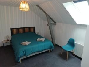 ein Schlafzimmer mit einem Bett und einem blauen Stuhl in der Unterkunft La Voilerie in Fécamp