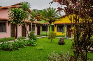 un jardin en face d'une maison avec des palmiers dans l'établissement Pousada Lapônia, à Penedo