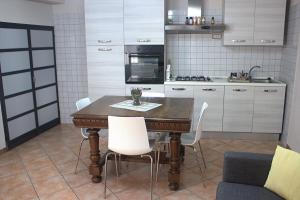 cocina con mesa de madera y sillas blancas en Casa Graziella - la casetta, en Portacomaro