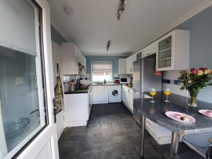 a kitchen with white cabinets and a table with wine glasses at PREMIER - Kenilworth House in Holytown