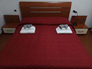 sypialnia z czerwonym łóżkiem z białymi butami w obiekcie NICOLE COUNTRY APARTMENTS w mieście Cassacco