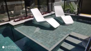two white chairs sitting next to a swimming pool at Design 205 - Quarto e Sala 42 M2- NOVO - Ponta Verde - Maceió in Maceió