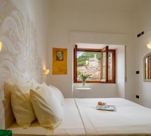 una camera da letto con un grande letto bianco e una finestra di Hotel San Francesco e il lupo a Gubbio