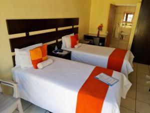 two beds in a hotel room with a bathroom at Katlego guest house in Welkom