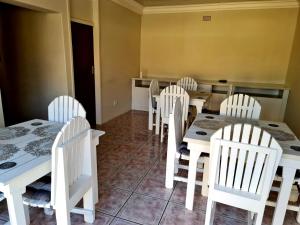 a dining room with white tables and white chairs at Katlego guest house in Welkom