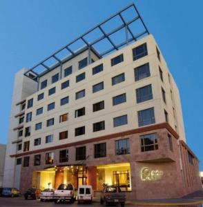 un grand bâtiment avec des voitures garées devant lui dans l'établissement Austral Plaza Hotel, à Comodoro Rivadavia