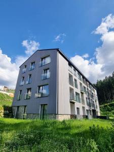 a building in a field next to a grassy field at Galeria Apartments - Jasná in Demanovska Dolina