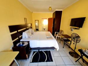 a bedroom with a bed and a desk and a tv at Katlego guest house in Welkom