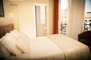 1 dormitorio con cama blanca y balcón en Hotel Aliados, en Oporto