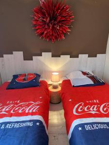 Zimmer mit 2 Coca-Cola-Betten und einem Kronleuchter in der Unterkunft La Canourguette in La Canourgue