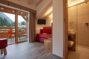 a room with a red bed and a balcony at Resort Dolce Casa - Family & Spa Hotel in Moena