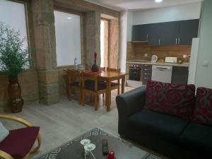 ein Wohnzimmer mit einem Sofa und einem Tisch sowie eine Küche in der Unterkunft Rustic House Fundão in Fundão