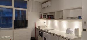 Una cocina blanca con fregadero y televisor. en Sentí el Mar.., en Punta del Este 16 fotos más