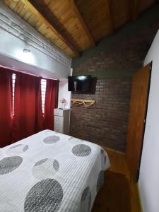 um quarto com uma cama e uma parede de tijolos em Deseo de Montaña em Maipú