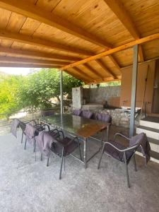 a table and chairs under a wooden roof at Holiday home Ramovic in Virpazar