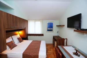 a hotel room with a bed and a flat screen tv at Apartments Ivana - Iva in Zadar