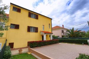 una casa amarilla con un patio delante en Apartments Ivana - Iva, en Zadar