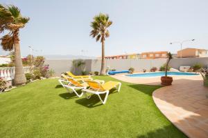a yard with lawn chairs and a swimming pool at MEDANO4YOU Casa Girasol in El Médano