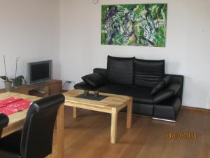sala de estar con sofá negro y mesa en Ferienwohnung Schmid en Hagnau