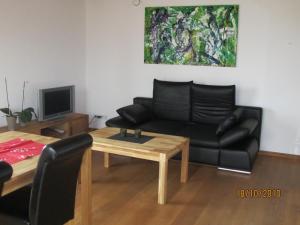 a living room with a black couch and a table at Ferienwohnung Schmid in Hagnau