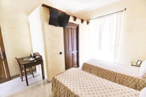 Zimmer mit 2 Betten, einem Schreibtisch und einem TV in der Unterkunft Dè Ajala - B&B de Charme in Làconi