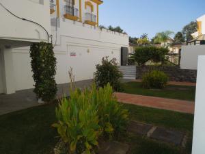 a white house with plants in the yard at Residencial Golf Playa IV in Islantilla