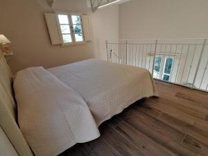 um quarto com uma cama branca e piso em madeira em Fattoria Ceragioli em Camaiore