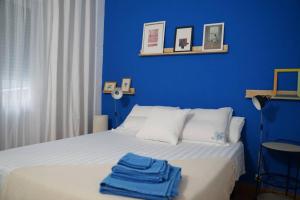 a blue bedroom with a bed with two towels on it at Apartamento Único en Plaza del Pilar in Zaragoza