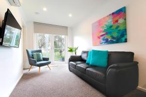 a living room with a black couch and a chair at Apartments 521 in Warrnambool