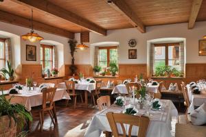 a restaurant with white tables and chairs and windows at Berggasthaus Weingarten in Ruhpolding