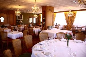 a dining room with white tables and chairs and chandeliers at Hostellerie Reeb in Marlenheim