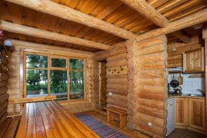 a log cabin kitchen with a large window at Atpūtas komplekss Godeļi in Usma +60 photos