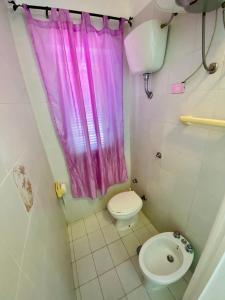 ein Badezimmer mit einem rosa Duschvorhang und einem WC in der Unterkunft Vacanzlucido in San Lucido