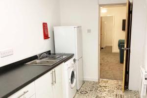 a kitchen with a sink and a refrigerator at Sutton Contractor Accommodation - Warrington, St Helens in Clock Face