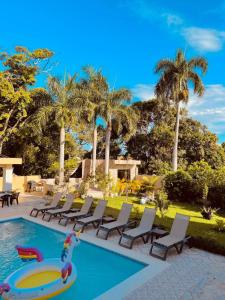 a swimming pool with lounge chairs and a pool noodle in the middle at Estancia Las Mercedes in San Felipe de Puerto Plata