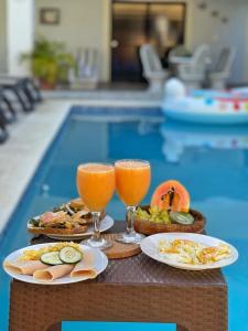 two glasses of orange juice and food on a table near a swimming pool at Estancia Las Mercedes in San Felipe de Puerto Plata