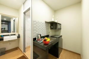a kitchen with a counter with a bowl of fruit on it at Metro Hotel Ratchada 36 in Bangkok +29 photos