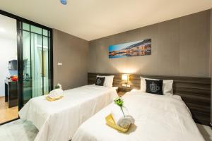 a bedroom with two beds with white sheets at Metro Hotel Ratchada 36 in Bangkok