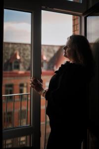 a woman standing in front of a window looking out at Hotel Continental Relax & Spa in Halmstad