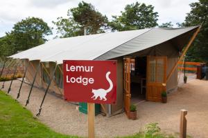 a sign in front of a tent with a lizard lodge at Durrell Wildlife Camp in Trinity
